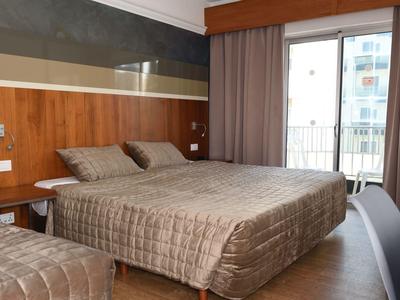 Modernes Hotelzimmer mit Doppelbett, Holzvertäfelung und Balkonblick.