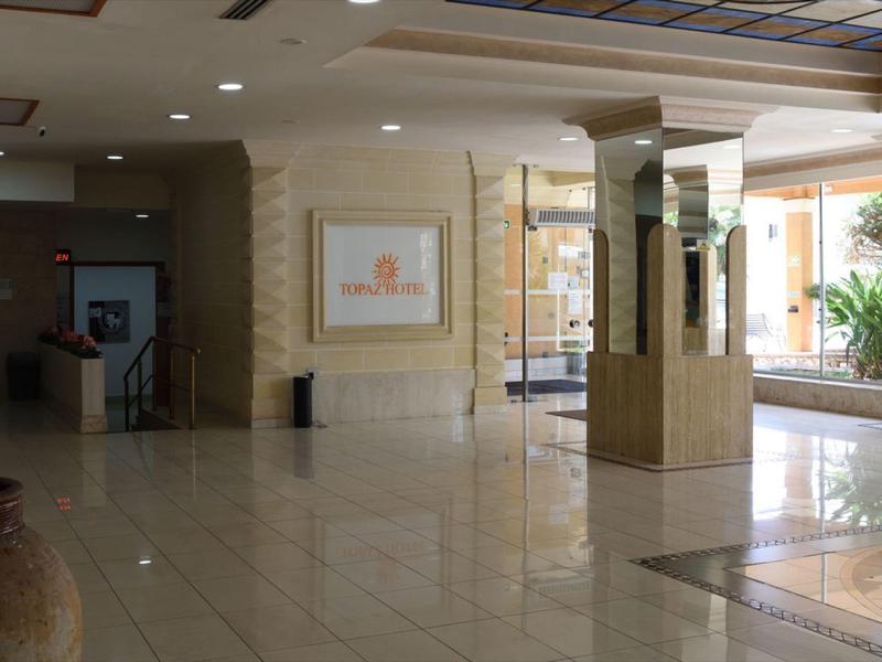 Světlá hotelová lobby s lesklou mramorovou podlahou a uměním na zdech