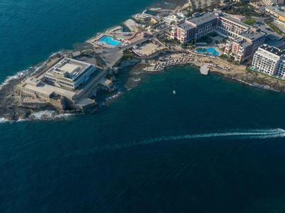 Luftaufnahme einer kleinen Halbinsel mit Hotels und einem Pool am Meer