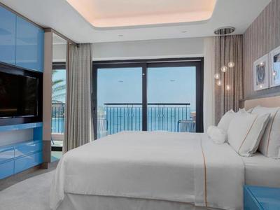 Schlafzimmer mit großem Bett und Blick auf Balkon mit Meerblick.