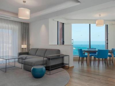 Modern eingerichtetes Wohnzimmer und Essbereich mit Meerblick und großen Fenstern.