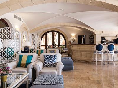 Elegantes Hotelzimmer mit bequemen Sesseln, Barbereich und Bogenfenstern.