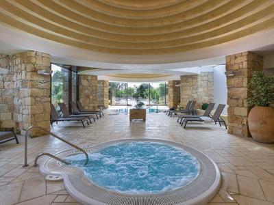 Innenbereich mit beheiztem Whirlpool und Liegestühlen in einem Hotelspa.