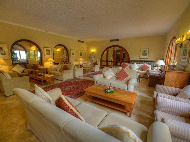 Amplia y acogedora zona de salón del hotel con sofás, sillones y luz cálida.