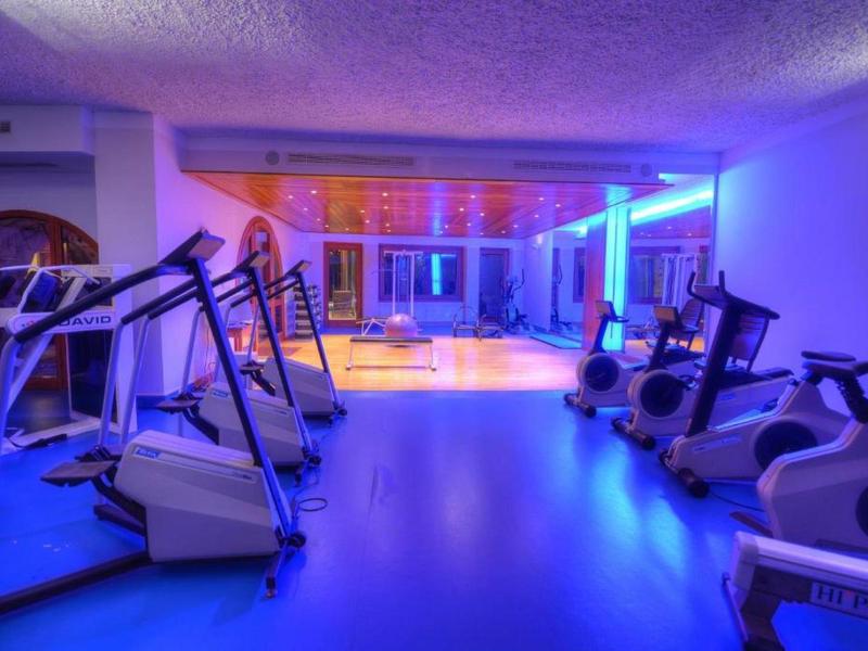 Gimnasio iluminado junto a una piscina con equipo moderno y luz azul.