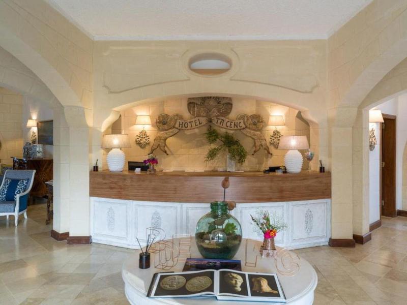 Elegante vestíbulo de hotel con recepción, planta decorativa y área de descanso cómoda.