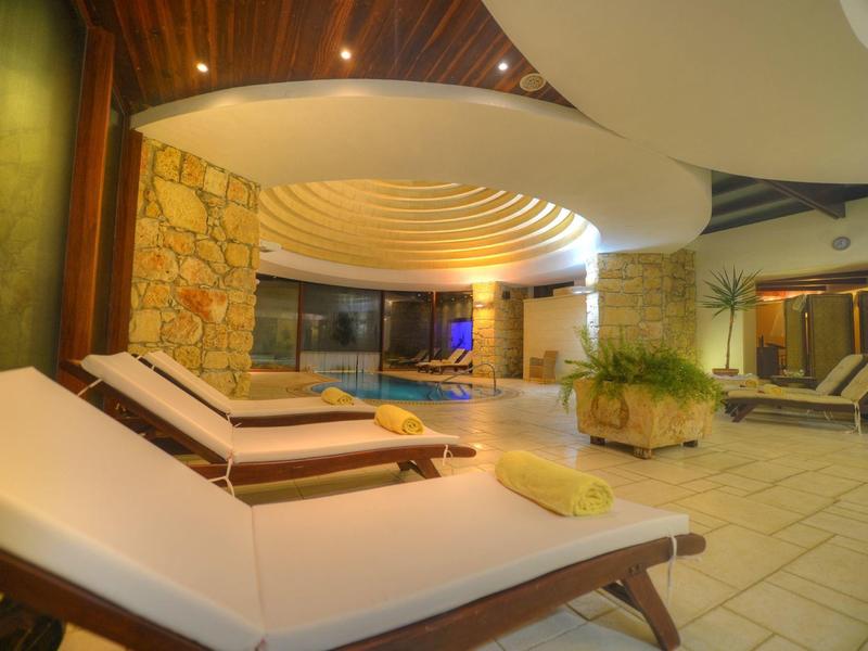 Zona de spa interior con tumbonas, piscina e iluminación relajante.