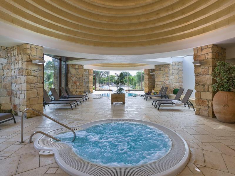 Área moderna de jacuzzi con tumbonas en un espacio abierto y elegante con columnas de piedra.