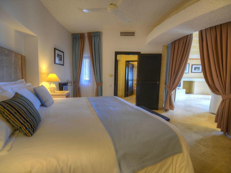 Cómoda habitación de hotel con una cama grande, iluminación y cortinas que conducen al baño.