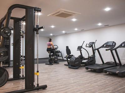 Bright gym with modern equipment and a person on a stationary bike.
