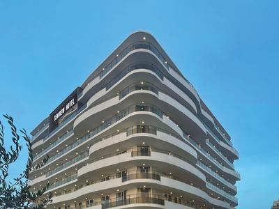 Modern multi-story hotel complex with curved balconies at dusk.