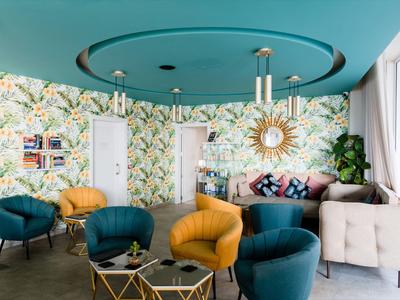 Modern lounge area with floral wallpaper, comfortable sofas, and a round mirror on the wall.