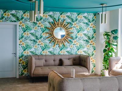 Modern lounge area with floral wallpaper, comfortable sofas, and a round mirror on the wall.