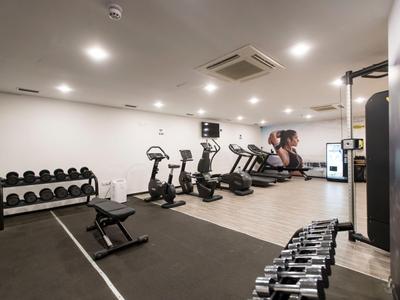 Modern gym with treadmills, bikes, dumbbells, and a large mirror.