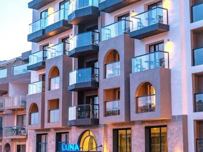 Edificio de hotel de varios pisos con balcones y letrero azul iluminado durante el día