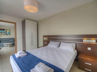 Habitación de hotel con cama doble, paredes blancas, mesitas de noche y armario al fondo.