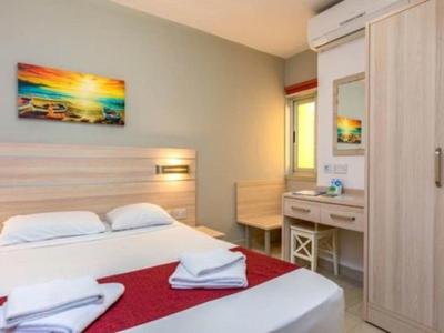 Acogedora habitación de hotel con cama doble, escritorio, armario y cuadro iluminados por la luz del día.