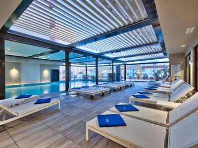 Moderner Innenpool mit Liegestühlen und großen Fenstern, die natürliches Licht einlassen.