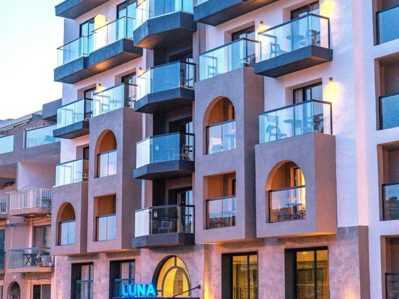 Edificio de hotel de varios pisos con balcones y letrero azul iluminado durante el día