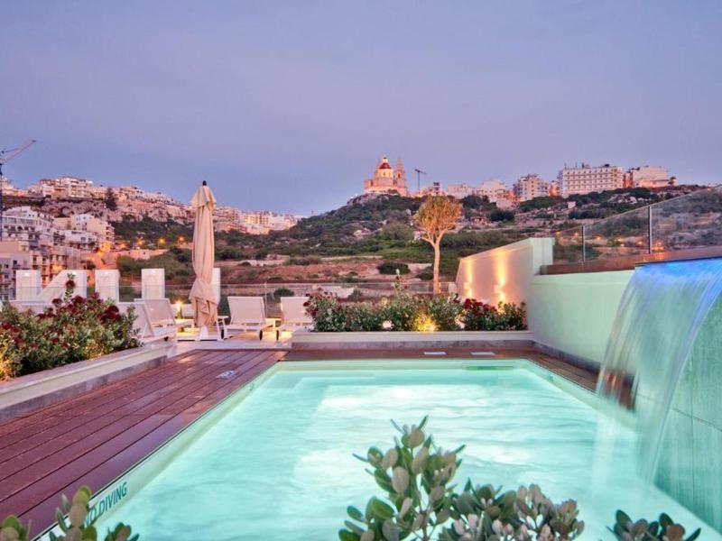 Piscina moderna con cascada y vista a la ciudad al atardecer