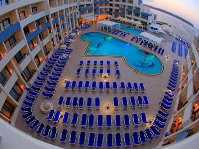 Hotel mit großem Pool und vielen blauen Liegestühlen auf einer Terrasse