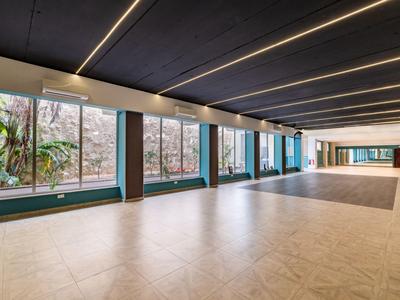 Großer Innenraum mit großen Fenstern, Blick auf eine Steinmauer und Pflanzen, moderner Bodenbelag.