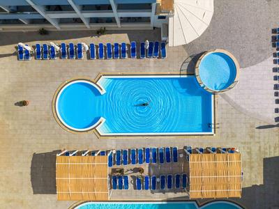 Vogelperspektive eines rechteckigen und runden Pools mit blauen Liegestühlen und Sonnenschirmen.