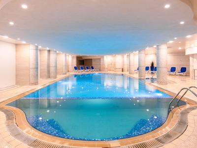 Innenpool in einem hellen, modernen Wellnessbereich mit blauer Beleuchtung.