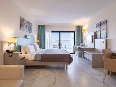 Modernes Hotelzimmer mit großem Bett, Balkon und Meerblick, heller Einrichtung und heller Atmosphäre.