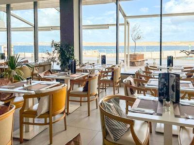 Elegantes Restaurant mit Meerblick und modernen Holzmöbeln am Strand.