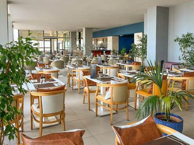 Hell und einladend gestalteter Frühstücksraum mit modernen Holzmöbeln und grünen Pflanzen.