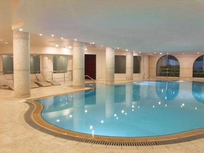 Overdekt zwembad met afgeronde vorm, zuilen en grote ramen in een luxe hotel.