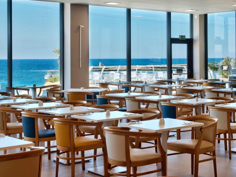 Licht restaurant met houten stoelen en zeezicht door grote ramen