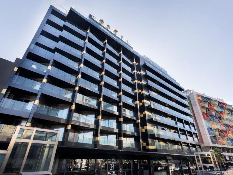 Modern multi-story hotel with glass balconies and clean lines in daylight.