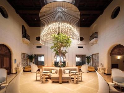 Großer Hotellobby mit runder Sitzgruppe und einem auffälligen Kronleuchter an der Decke.