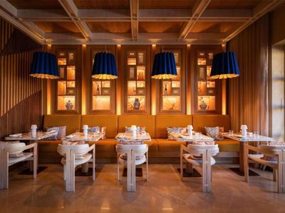 Elegantes Hotelrestaurant mit Holztischen und moderner Beleuchtung in warmem Ambiente.