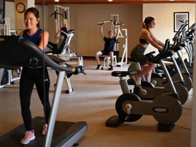 Fitnessraum mit mehreren Personen, die auf Laufbändern und anderen Geräten trainieren.