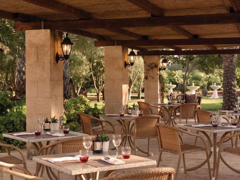 Pohodlná venkovní terasa s prostřenými stoly a židlemi pod dřevěnou střechou.