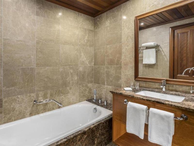 Moderní koupelnový prostor s vanou, umyvadlem a zrcadlem v dřevěném rámu.