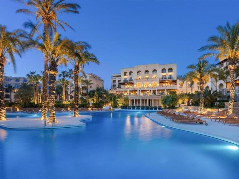 Luxusní hotel s osvětleným bazénem a palmami za soumraku