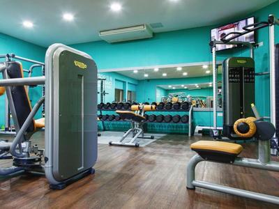 Palestra moderna con macchine per forza, manubri e pavimento in legno in un hotel.