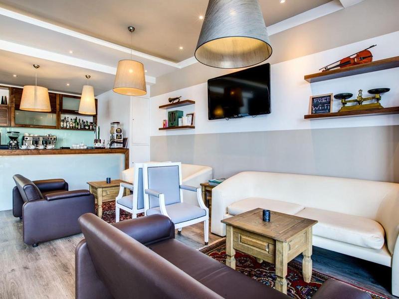 Pohodlná hotelová lounge s pohovkami, křesly a televizí na zdi.