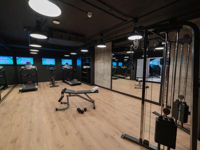 Gimnasio moderno con suelo de madera, equipo de entrenamiento y pared de espejos en hotel