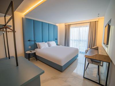 Habitatión de hotel moderna con cama grande, escritorio y ventana con cortinas.