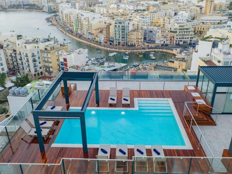 Modern zwembad op het dak met uitzicht op een stad en haven.