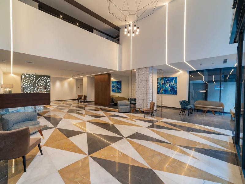 Moderne hotelreceptie met geometrisch vloerenpatroon, fauteuils en heldere verlichting