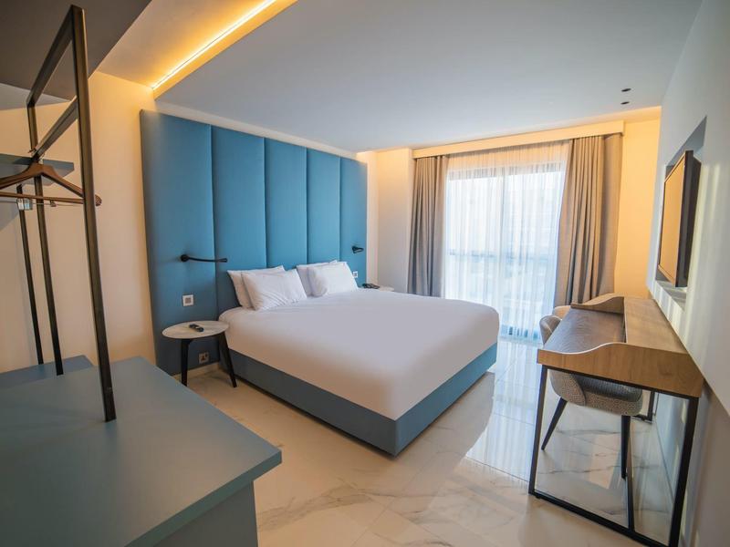 Moderne hotelkamer met groot bed, bureau en blauwe gestoffeerde muur.