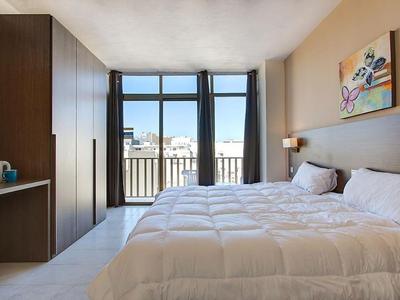 Habitación de hotel moderna con cama doble, ventana grande y vista a la ciudad.