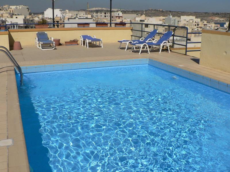 Piscina azzurra limpida su una terrazza con lettini e vista sulla città
