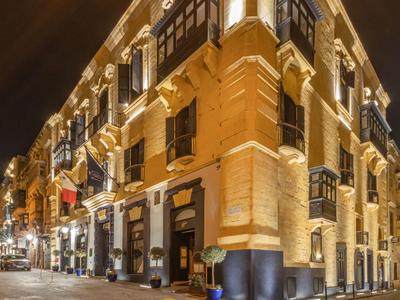 Beleuchtetes historisches Gebäude an belebter Straßenecke bei Nacht.